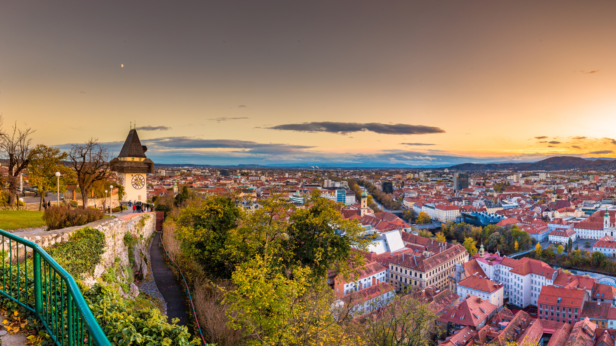 Book a taxi in Graz – panoramic view with Clock Tower and Schlossberg at sunset